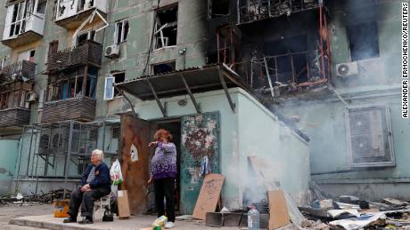 Locals are seen outside the apartment building destroyed in Mariupol on April 28, 2022. 