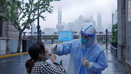 Um trabalhador médico com equipamento de proteção coleta uma amostra de cotonete de um residente de Xangai em 26 de abril de 2022.