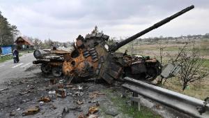 A man ride a motorbike past a destroyed Russian tank on a road in the Kyiv region on April 16.