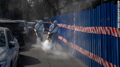 Health workers wear protective suits as they disinfect an area outside a barricaded community that was locked down for health monitoring after recent cases of Covid-19 were found in the area on March 28, in Beijing, China. 