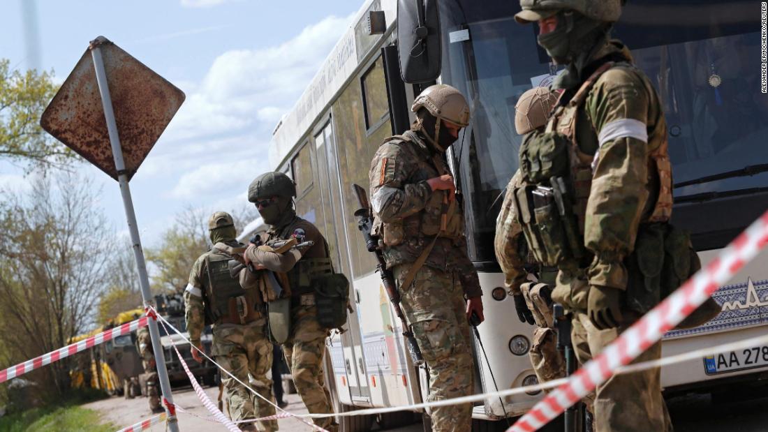 Pro-Russian troops stand guard next to a bus transporting evacuees near a temporary accommodation center in the Ukrainian village of Bezimenne on May 1.