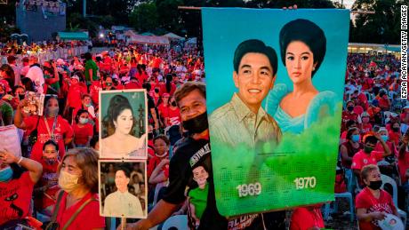 A Marcos supporter holds pictures of the late dictator Ferdinand and his wife Imelda, as Ferdinand &quot;Bongbong&quot; Marcos Jr. holds a campaign rally, in February this year. 