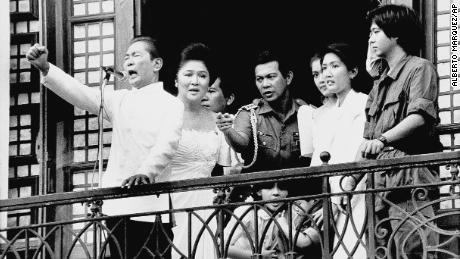 فرديناند ماركوس ، مع زوجته إيميلدا إلى جانبه وفيرديناند ماركوس جونيور ، أقصى اليمين ، على شرفة قصر مالاكانانج في 25 فبراير 1986 في مانيلا.