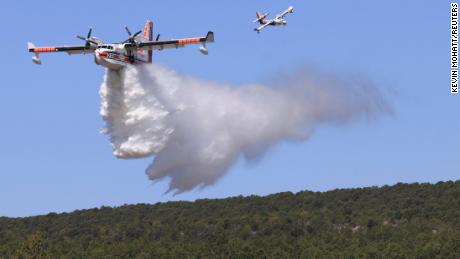 Çarşamba günü Hermits Peak / Calf Canyon Fire ile savaşmak için bir uçak su döküyor.