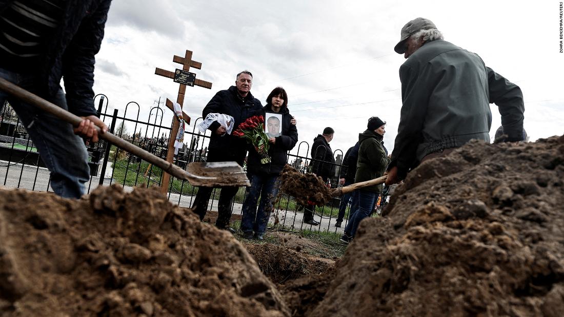 Maria, 13, holds a photograph of her father, Yurii Alekseev, as she and her godfather, Igor Tarkovskii, attend Alekseev&#39;s funeral in Bucha, Ukraine, on April 26. Alekseev, 50, was a territorial defense member who was killed by Russian soldiers, according to his family.