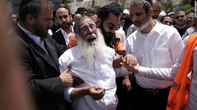 Ultra-Orthodox Jewish mourners encircle a man overcome with grief following the attack.