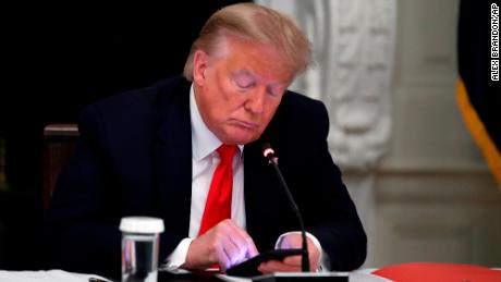 Former President Donald Trump looks at his phone during a roundtable discussion with governors about the reopening of US small businesses, in the State Dining Room in the White House in Washington, June 18, 2020. 