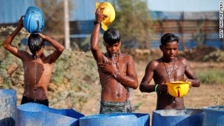 Workers use their helmets to pour water to cool themselves down as a heatwave rages in India