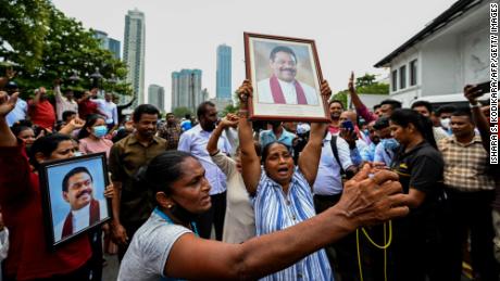 Pro-government supporters hold portrait of Prime Minister Rajapaksa while protesting outside his residence in Colombo.