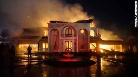 يعمل رجال الإطفاء على إطفاء مبنى محترق خلال حريق غابات الأربعاء في لاجونا نيكولاس ، كاليفورنيا.
