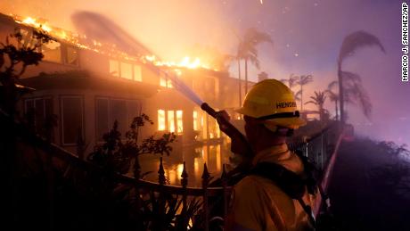Um bombeiro trabalha em um prédio em chamas na quarta-feira em Laguna Nicole.