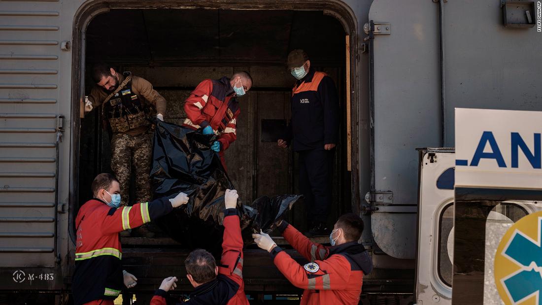 Ukrainian serviceman and emergency workers carry the body of a Russian soldier into a refrigerated train in Kharkiv on May 5. The bodies of more than 40 Russian soldiers were being stored in the refrigerated car. 