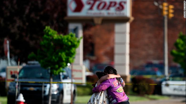 People hug near the scene of the mass shooting at the Tops Friendly Markets store Saturday.