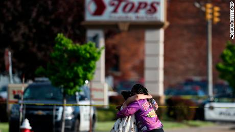 La gente se abraza fuera de la escena de un tiroteo en un supermercado en Buffalo el sábado.