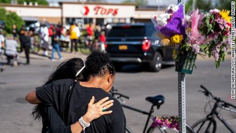 BUFFALO, NY - MAY 15: Jeanne LeGall, of Buffalo, hugs Claudia Carballada, of Buffalo, as she gets emotional, as she pays her respects at an makeshift memorial as people gather at the scene of a mass shooting at Tops Friendly Market at Jefferson Avenue and Riley Street on Sunday, May 15, 2022 in Buffalo, NY. The fatal shooting of 10 people at a grocery store in a historically Black neighborhood of Buffalo by a young white gunman is being investigated as a hate crime and an act of racially motivated violent extremism, according to federal officials. (Kent Nishimura / Los Angeles Times via Getty Images)