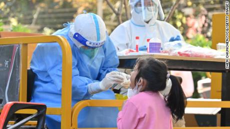 SHANGHAI, CHINA - APRIL 09: A medical worker takes nucleic acid samples from a child at a gated community after Shanghai imposed a citywide lockdown to halt the spread of COVID-19 epidemic on April 9, 2022 in Shanghai, China. (Photo by Shen Chunchen/VCG via Getty Images)