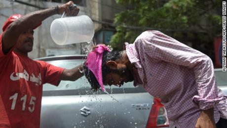 An Edhi volunteer pours water on a pedestrian along a street during a hot summer day in Karachi on May 16.