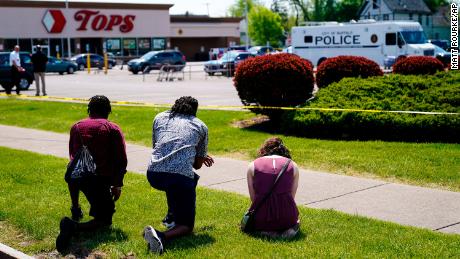 People pray outside the scene of Saturday&#39;s shooting at the Tops supermarket in Buffalo.