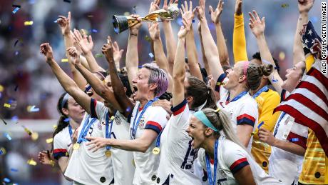 Megan Rapinoe lifts the FIFA Women's World Cup trophy as her team celebrates the victory of the 2019 tournament. 
