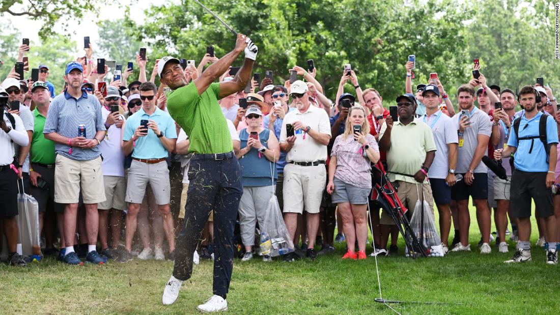 Tiger Woods plays his second shot on the first hole as a gallery of fans look on during the second round.
