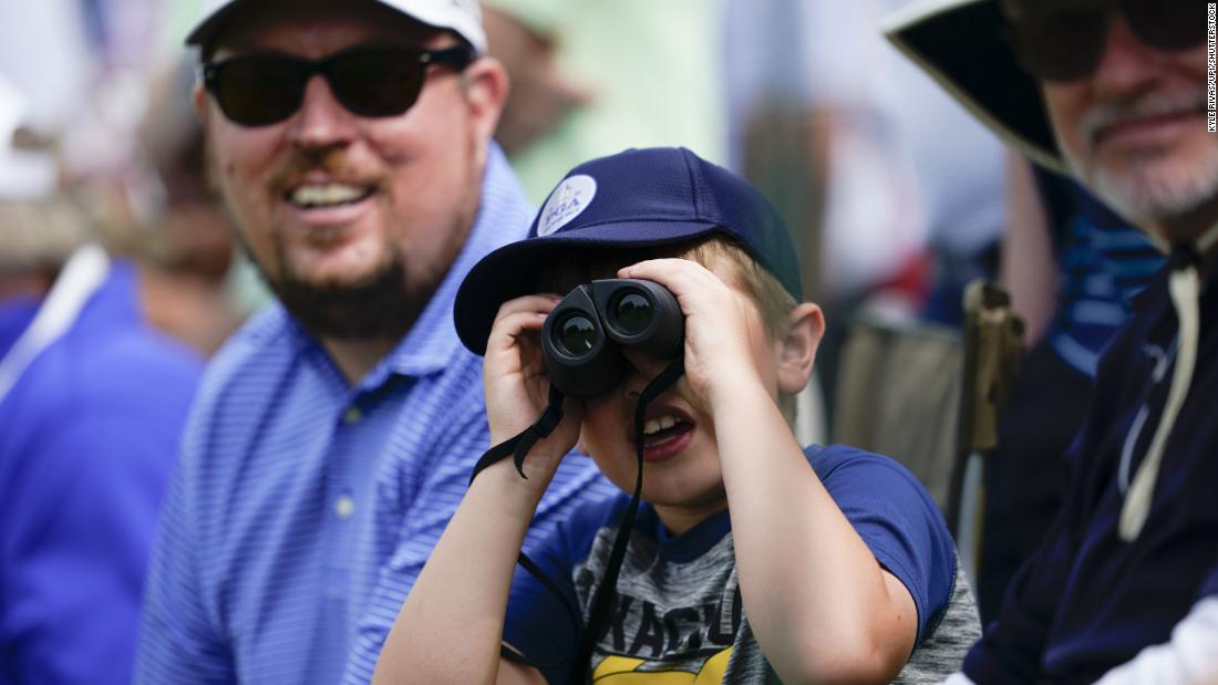 A young spectator views players through binoculars during the second round.