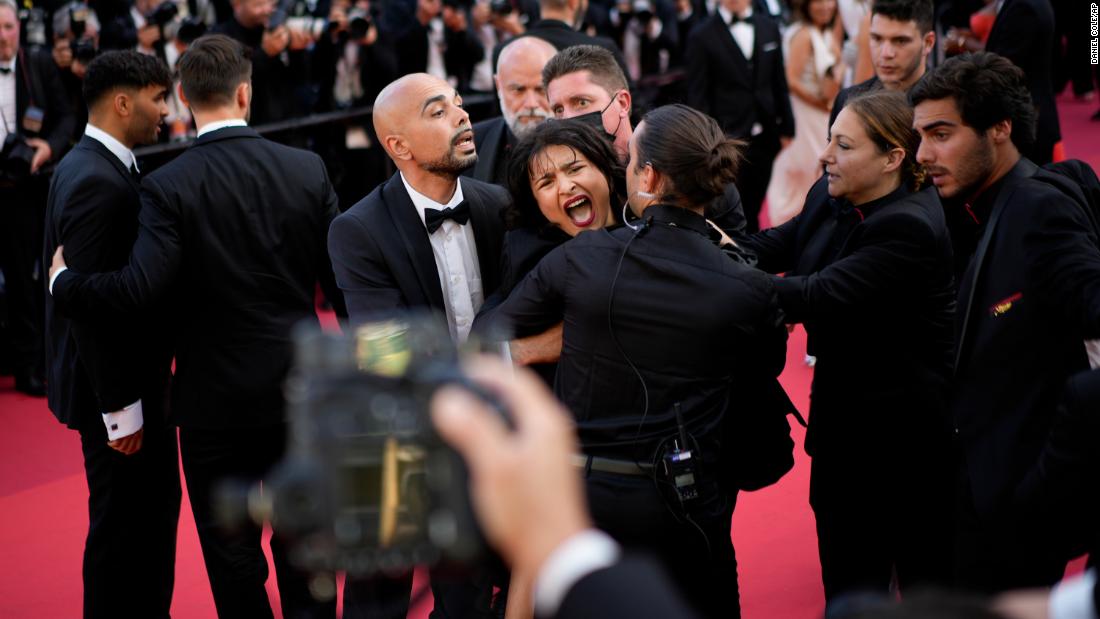 Topless protester with blue and yellow paint across her body storms Cannes red carpet to denounce sexual violence in Ukraine
