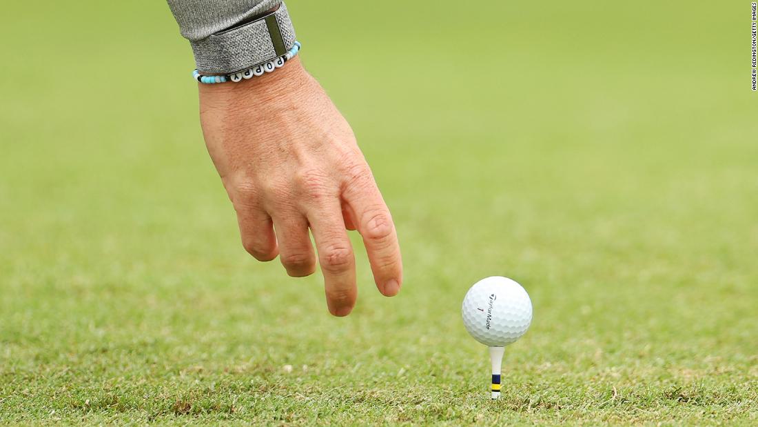 Rory McIlroy places his golf ball on the fourth tee wearing a bracelet with his daughter&#39;s name on it.