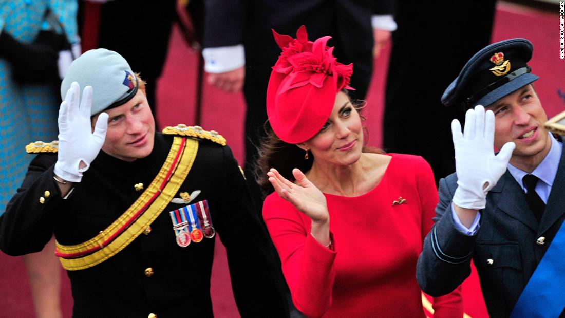 Catherine, Duchess of Cambridge, Prince William and Prince Harry wave as they pass the Houses of Parliament aboard the royal barge.