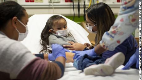 Study participant Elena Rosales (center), 3, receives the Moderna Covid-19 vaccine from nurse Lela Lartey (left) with her mother Mariaelena Lozano (right) by her side, at Chicago's 7th s Hospital.