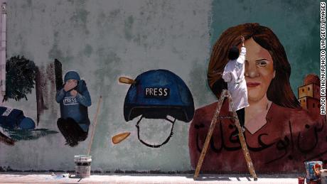 A Palestinian artist paints a mural in Gaza City honoring Shireen Abu Akleh, and depicting Shatha Hanaysha crouching beside her after she was killed. 