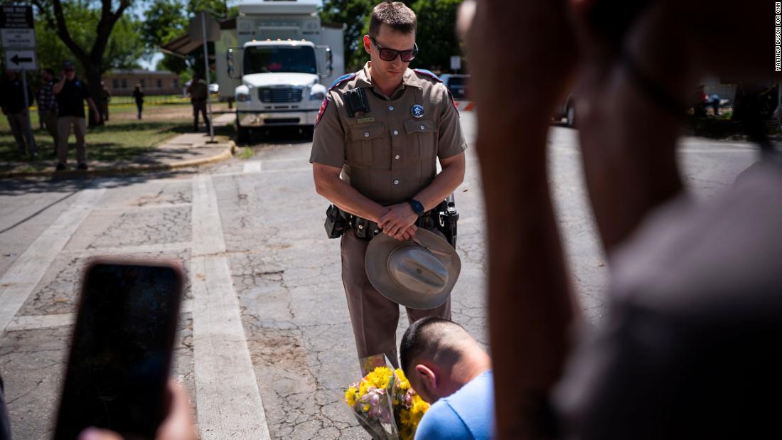 An officer with the Texas Highway Patrol prays with a community member before taking his flowers to the growing memorial in front of Robb Elementary School.