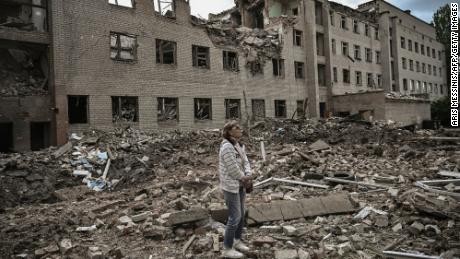 A woman stands in front of a destroyed administration building in the city of Bakhmut in the eastern Ukranian region of Donbas, on May 25, 2022. (Photo by ARIS MESSINIS / AFP) (Photo by ARIS MESSINIS/AFP via Getty Images)