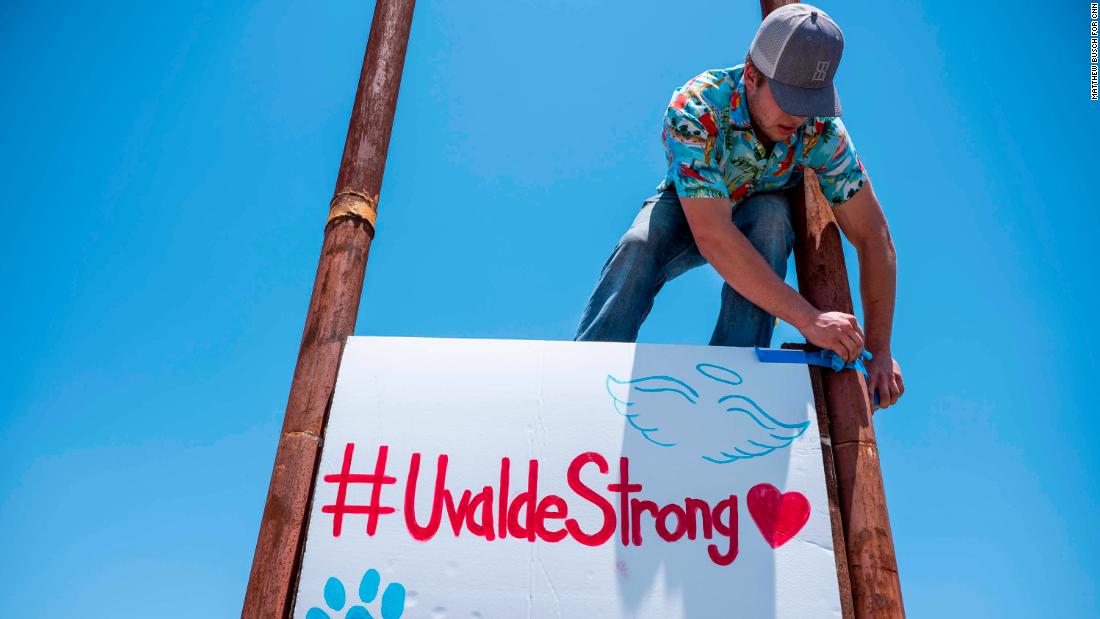 Tyler Garcia raises up a sign during a car wash and food sale on Thursday to raise money for the families of those who lost loved ones in the Robb Elementary School shooting. 
