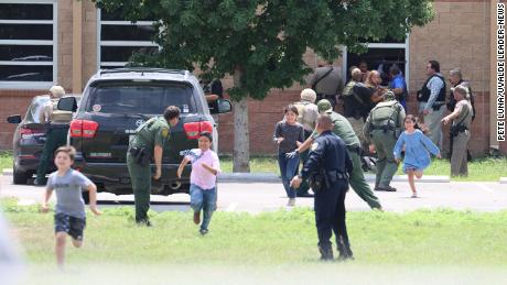 Students run to safety after escaping from a window at Robb Elementary School on Tuesday.