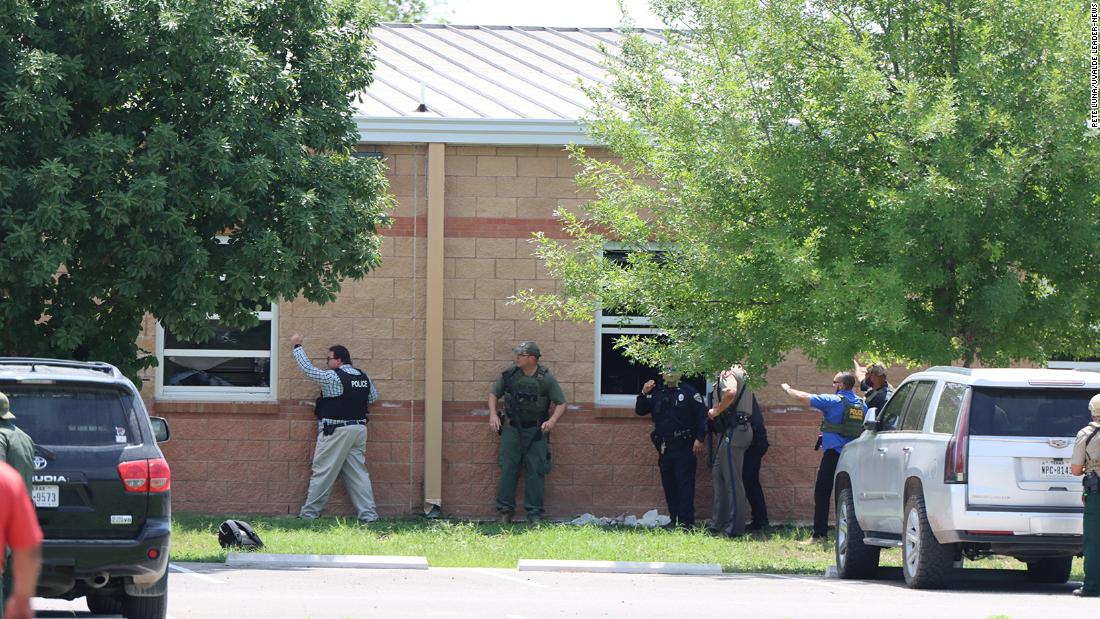 Law enforcement works near a school window before helping children out.
