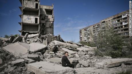 Zēns sēž uz ēkas drupām, kas ievainotas reidā Doņeckas apgabala pilsētā Kramatorskā.