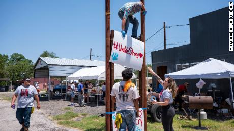 Tyler Garcia, 21 ans, en haut, lève une pancarte lors d'un lavage de voiture et d'une vente de nourriture pour collecter des fonds pour les familles des personnes tuées.