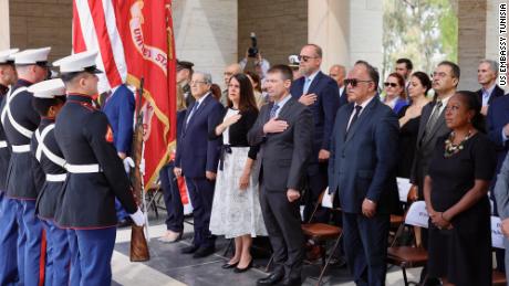 Attendees stand during the Memorial Day ceremony at the North African American Cemetery. Tunisian Foreign Minister Othman Jerendei (front row, left) stands next to US Embassy Tunisia Chargée d&#39;Affaires Natasha Franceschi.
