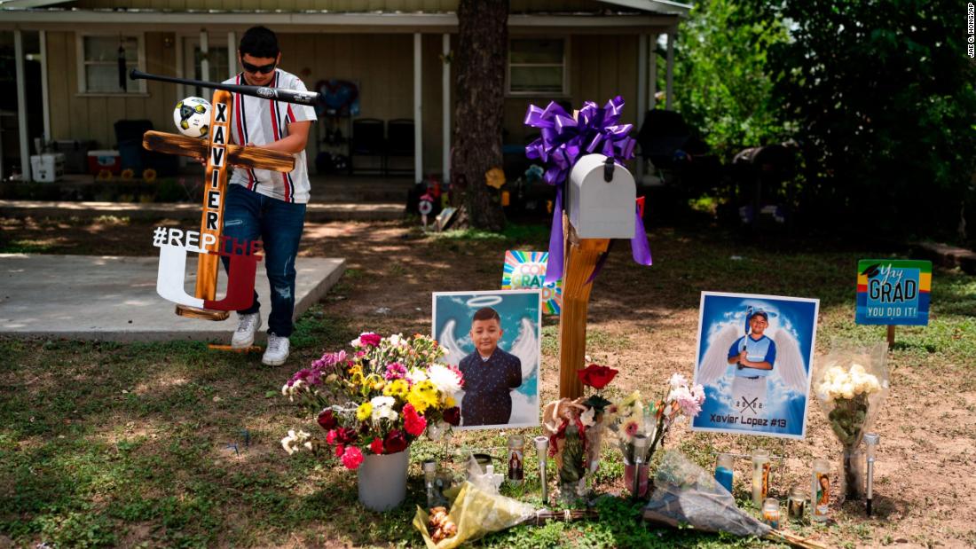 Jose Mata, brother of shooting victim Xavier Lopez, carries a wooden cross decorated with a baseball bat to place it at Xavier&#39;s memorial outside his home in Uvalde on May 31. 