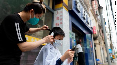 Un barbier coupe les cheveux d'un garçon dans une rue de Shanghai mercredi.