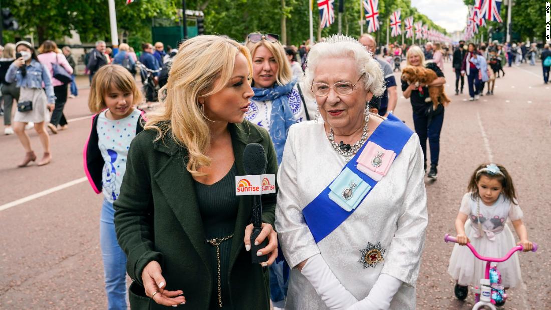 A Queen impersonator is interviewed as she walks along The Mall on Wednesday.