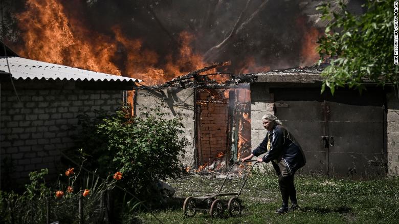 An elderly woman walks away from a burning house garage after shelling in the city of Lysytsansk at the eastern Ukrainian region of Donbas on May 30, 2022.