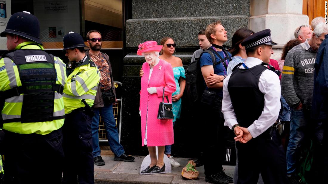 A woman holds a cutout picture of the Queen while waiting outside St Paul&#39;s Cathedral on Friday.