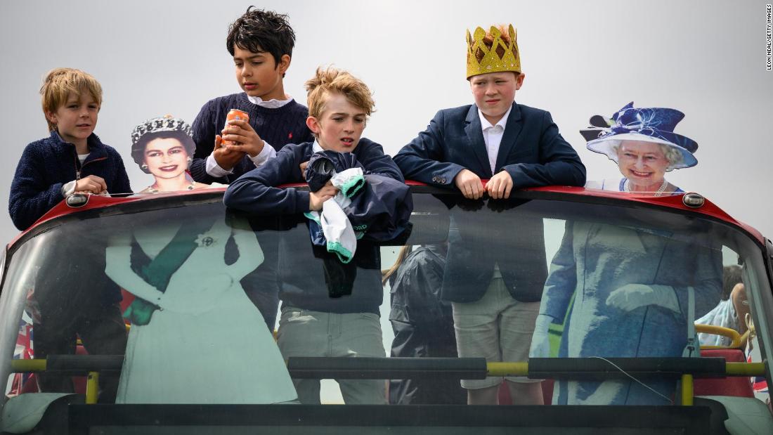 Boys ride a bus in Epsom alongside cardboard cutouts of the Queen.
