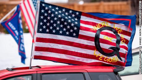 ST PAUL, MN - NOVEMBER 14: A car with a flag endorsing the QAnon drives by as supporters of President Donald Trump gather for a rally outside the Governor&#39;s Mansion on November 14, 2020 in St Paul, Minnesota. Thousands have gathered in cities around the country today to contest the results of the election earlier this month. (Photo by Stephen Maturen/Getty Images)