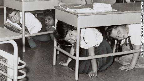 Students at a Brooklyn middle school 'duck and cover' during a practice drill for a nuclear attack in 1962.