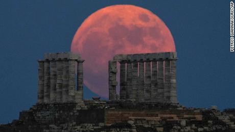Une pleine lune aux fraises se lève derrière le temple de Poséidon au cap Sounion, en Grèce, en juin 2021.