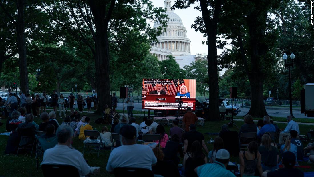 People gather in a park outside the Capitol to watch the hearing on June 9.