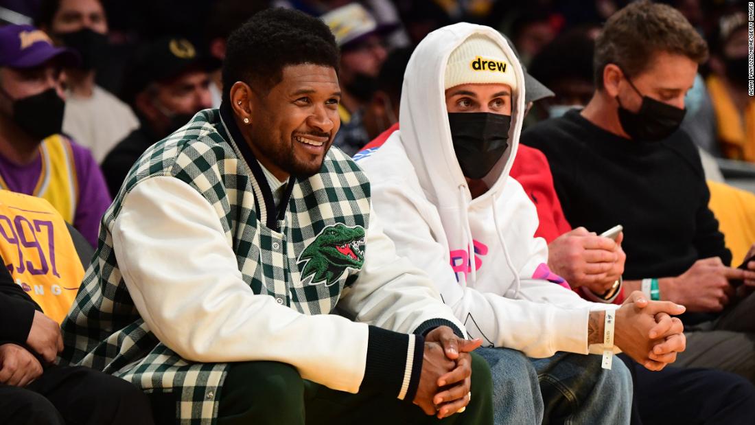 Bieber sits next to R&amp;amp;B singer Usher at an NBA game in Los Angeles in October 2021.