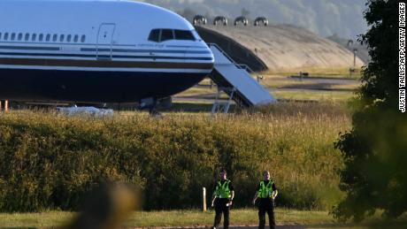 Two police officers walk in grounds near to where a Boeing 767 sits on the runway at the military base in Amesbury, Salisbury, on June 14, 2022, preparing to take a number of asylum-seekers to Rwanda. - The British government was to send a first plane carrying failed asylum seekers to Rwanda on Tuesday despite last-gasp legal bids and protests against the controversial policy. A chartered plane will land in Kigali on Tuesday, campaigners said, after UK judges rejected an appeal against the deportations. (Photo by JUSTIN TALLIS / AFP) (Photo by JUSTIN TALLIS/AFP via Getty Images)